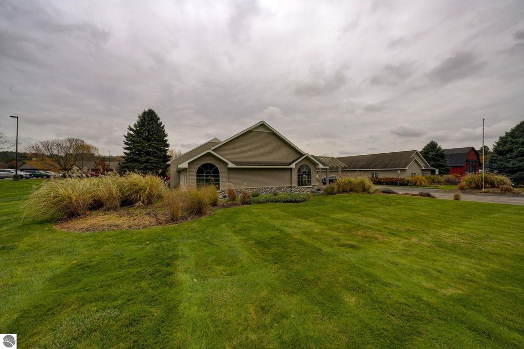 Commercial property exterior at 7200 E Duck Lake Road, Lake Leelanau, featuring landscaped grounds, two buildings, and a cloudy sky.