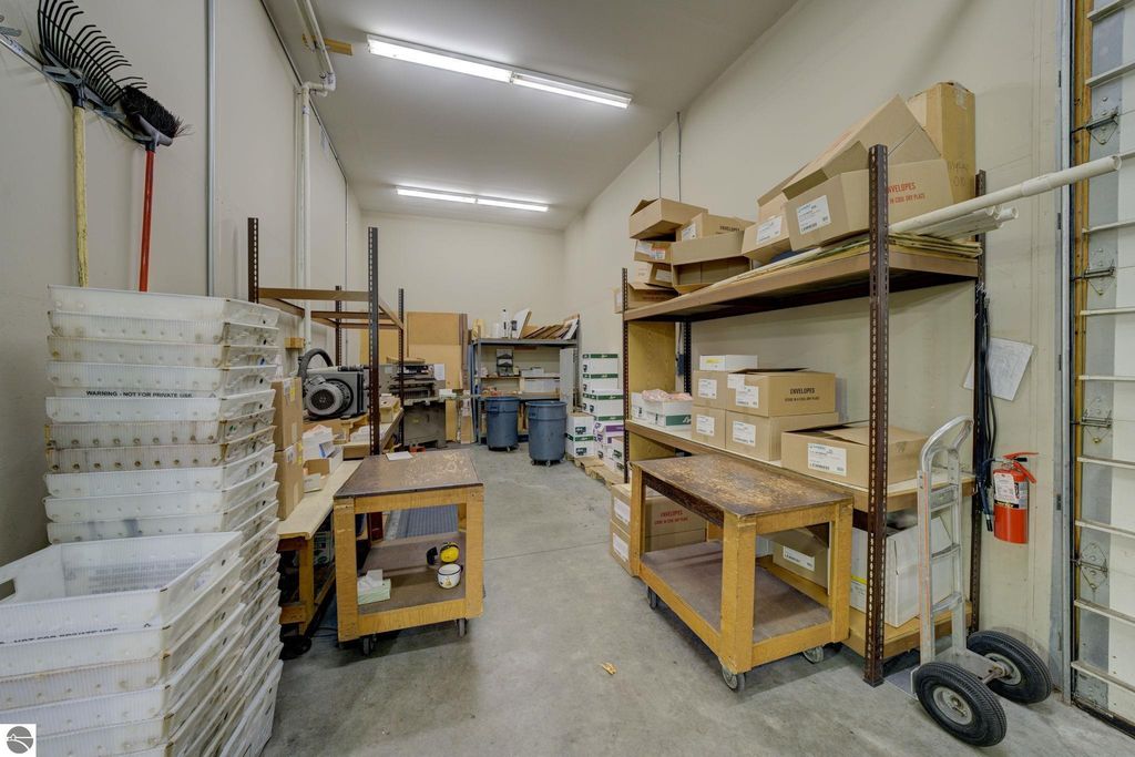 Storage area with shelving units, boxes, and workstations, showcasing flexible potential for commercial use in Lake Leelanau property listing.