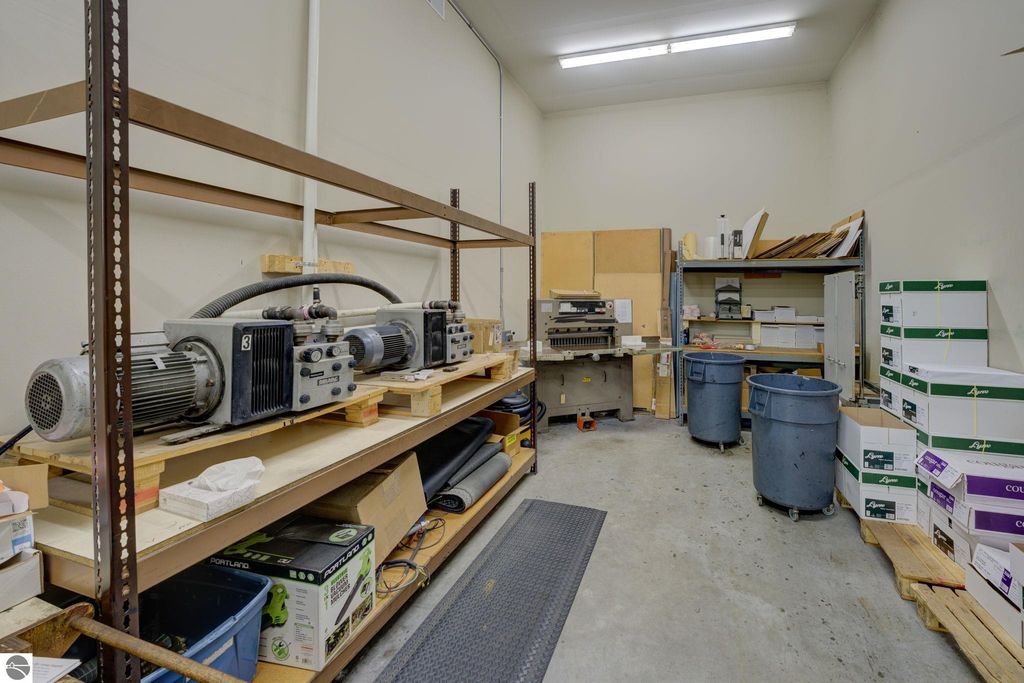 Storage area with industrial equipment, including motors on shelves, workstations, and storage containers, highlighting potential for flexible build-out in commercial property at 7200 E Duck Lake Road, Lake Leelanau, MI.