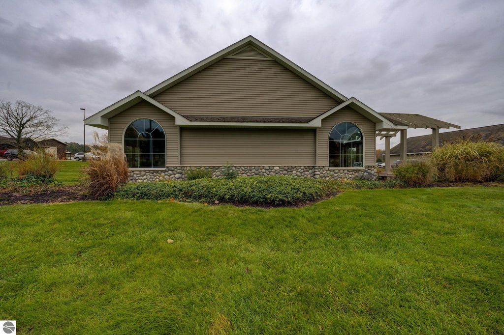 Commercial building exterior at 7200 E Duck Lake Road, Lake Leelanau, featuring landscaped grounds, stone foundation, large windows, and a covered entryway, highlighting investment potential in a growing community.
