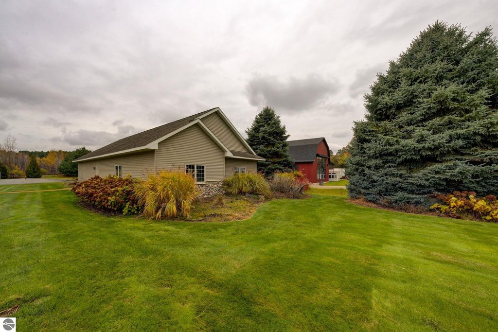 Commercial property exterior at 7200 E Duck Lake Road, Lake Leelanau, featuring two buildings on landscaped grounds with greenery and trees, showcasing investment potential in a growing community.