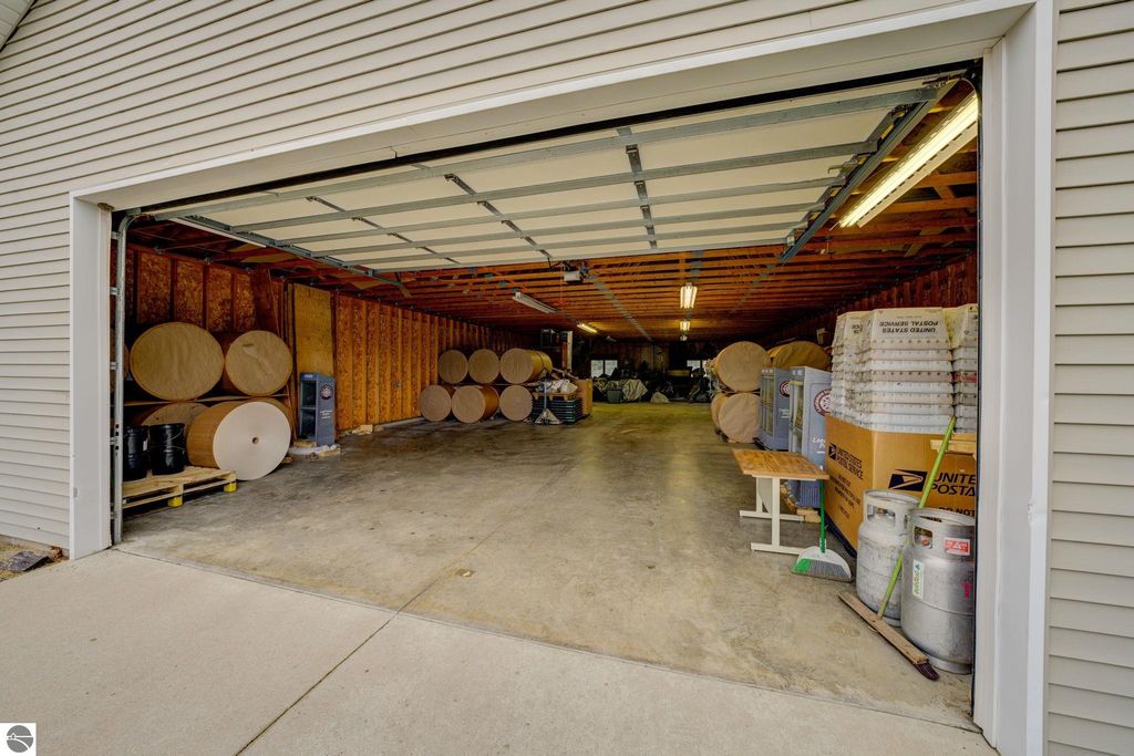 Garage interior with storage space, including large rolls of material, barrels, and boxes, showcasing flexible potential for commercial use in Lake Leelanau, MI.