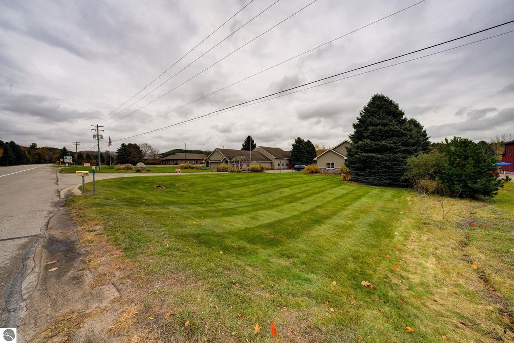 Commercial property exterior view at 7200 E Duck Lake Road, Lake Leelanau, showcasing landscaped lawn, nearby buildings, and roadside visibility along a business corridor.