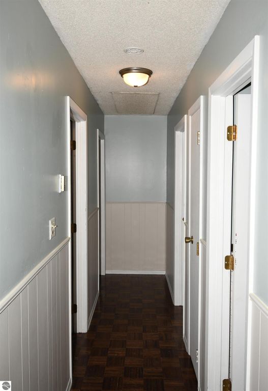 Hallway featuring white doors, gray walls, and parquet flooring in a ranch-style home at 2275 Noble Road, Tawas City, MI, showcasing comfortable living space.