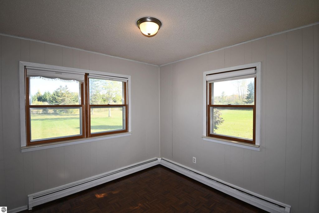 Ranch-style home interior featuring freshly painted walls, two windows showcasing outdoor greenery, and a ceiling light fixture, ideal for comfortable living in Tawas City on 40 acres.
