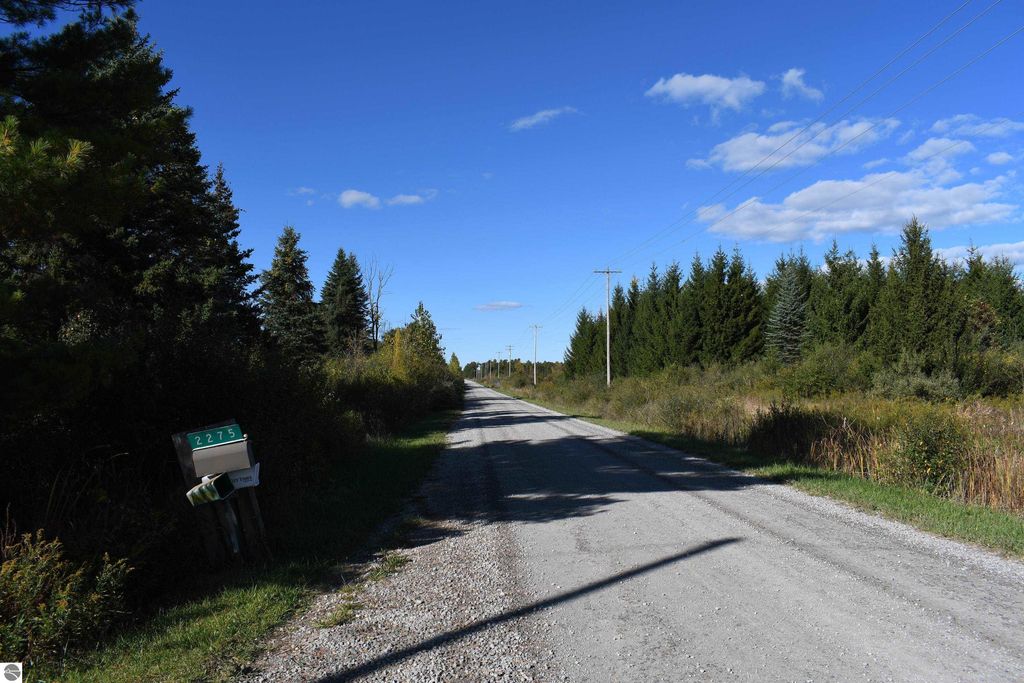 Gravel road leading to 2275 Noble Road, Tawas City, surrounded by trees and open land, showcasing the private 40-acre property for sale.