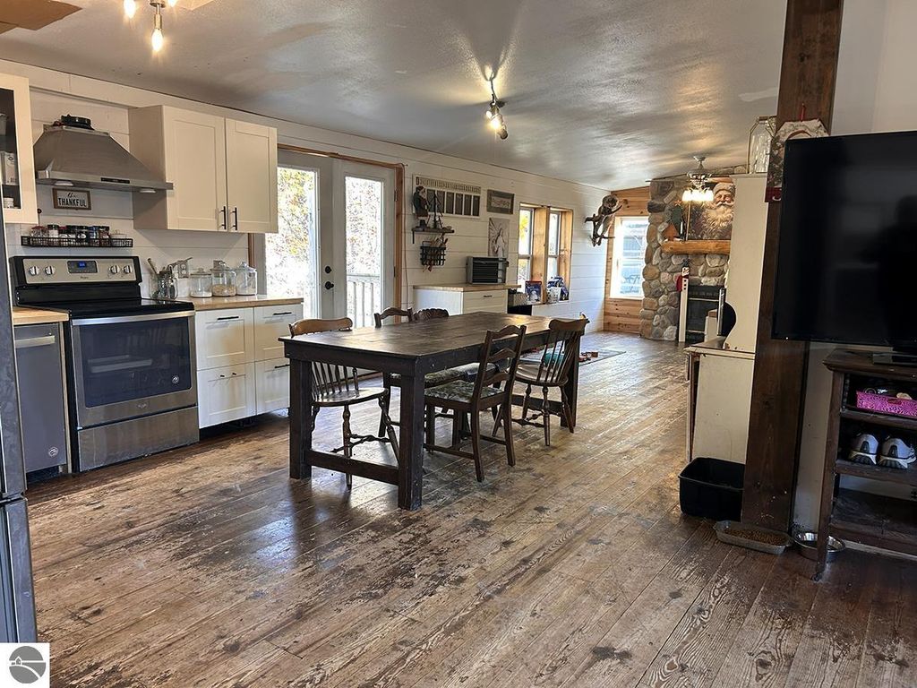 Cozy interior of a 3-bedroom, 2-bath home for sale in Rose City, MI, featuring a dining table, modern kitchen appliances, and rustic decor, highlighting the property’s potential for a peaceful retreat on 5.23 acres.