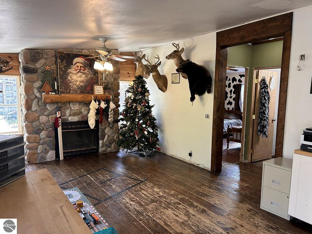 Cozy interior of a rustic home featuring a stone fireplace, Christmas tree, and mounted deer heads, reflecting a warm Up North retreat atmosphere.