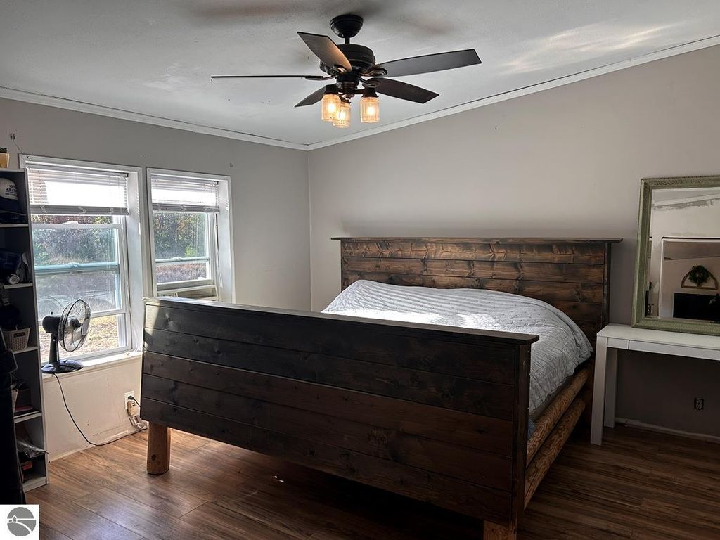 Cozy bedroom featuring a wooden bed frame, natural light from windows, and rustic decor, highlighting the potential for a peaceful retreat in Rose City, MI.