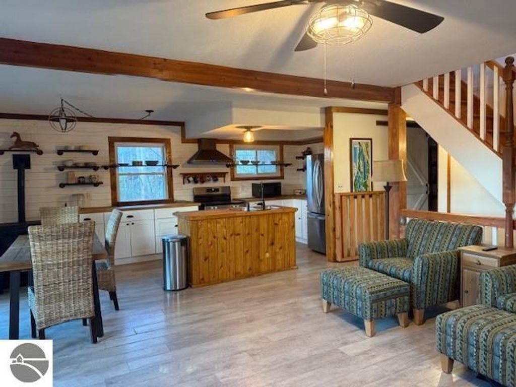 Chalet-style interior of a home featuring a wooden kitchen island, dining area with wicker chairs, and cozy seating, showcasing a natural and inviting atmosphere in Alden, MI.