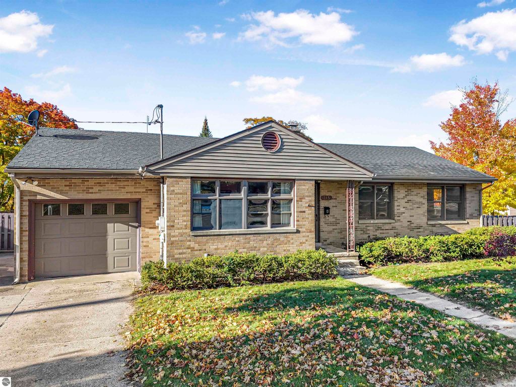 Charming ranch-style home at 315 N Simons Street, Cadillac, MI, featuring 3 bedrooms, 2 baths, and an attached garage, surrounded by fall foliage and a landscaped yard.