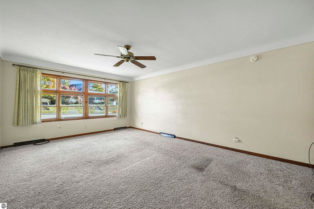 Spacious living room in a 3-bedroom ranch home at 315 N Simons Street, featuring large windows, ceiling fan, and neutral-colored walls, ideal for natural light and comfort.