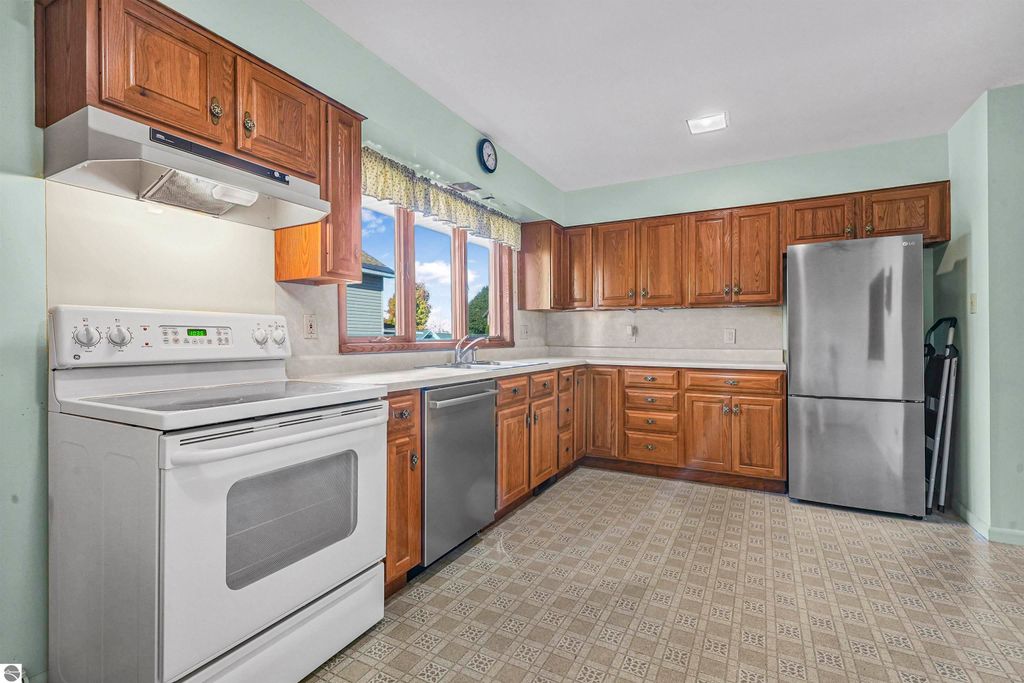 Kitchen interior featuring wooden cabinetry, stainless steel appliances, and ample natural light from windows, highlighting the spacious layout of the home at 315 N Simons Street, Cadillac, MI.