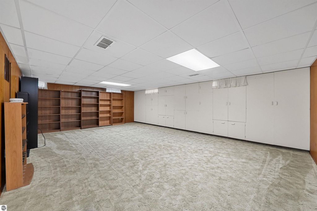 Finished basement with carpeted flooring, built-in shelving, and ample storage space, showcasing additional living area in 315 N Simons Street, Cadillac, MI real estate listing.