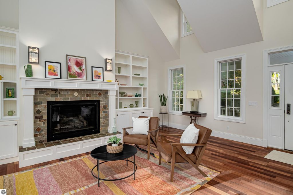Cozy great room featuring a gas fireplace, hardwood floors, and modern decor, showcasing a welcoming atmosphere in the Traverse City home for sale at 6436 Peregrin Court.
