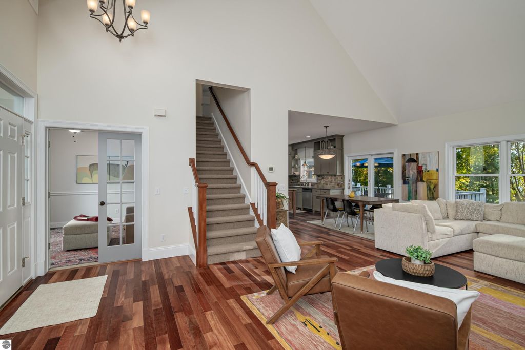 Spacious entryway of a custom-designed home at 6436 Peregrin Court, featuring hardwood floors, a staircase leading to upper levels, and an open layout connecting to a modern kitchen and living area, showcasing inviting decor and natural light.