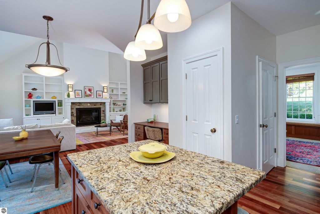 Kitchen interior of a custom-designed home at 6436 Peregrin Court, featuring granite countertops, hardwood floors, a cozy gas fireplace, and modern cabinetry, highlighting a blend of timeless architecture and contemporary style.
