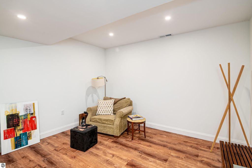 Cozy walkout lower level living area in Traverse City home featuring modern decor, hardwood floors, and artwork.