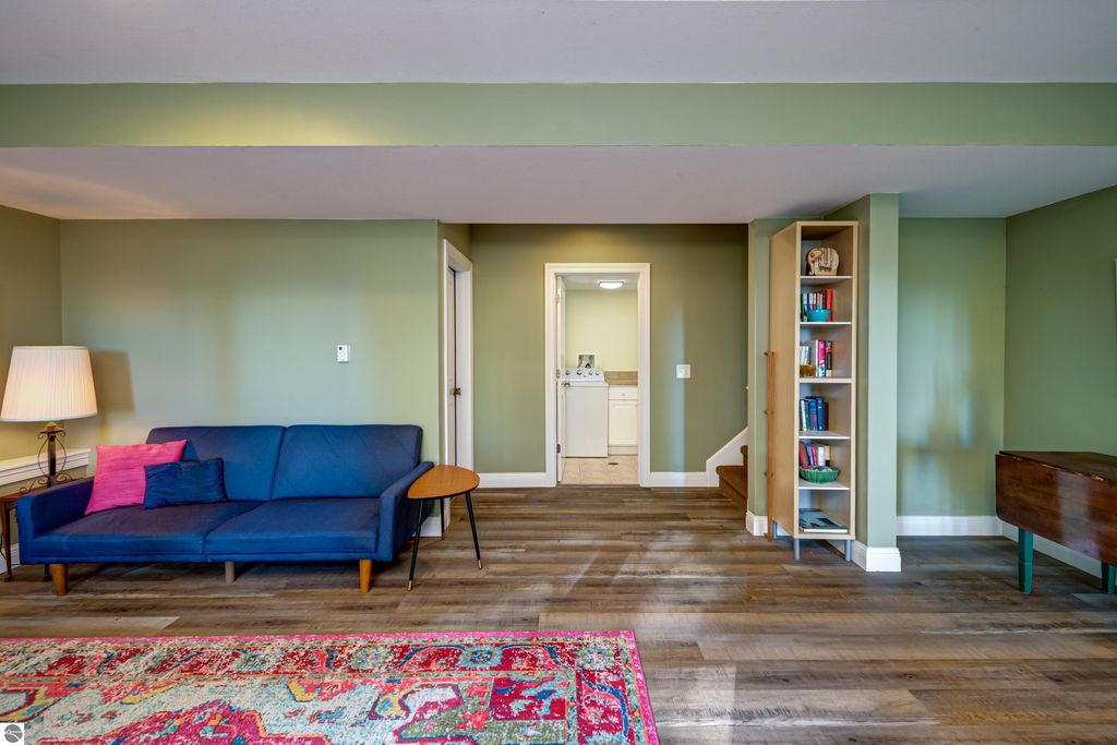 Interior living space of a home at 6436 Peregrin Court, featuring a blue sofa with colorful cushions, a decorative lamp, and a bookshelf, showcasing modern design and inviting atmosphere.