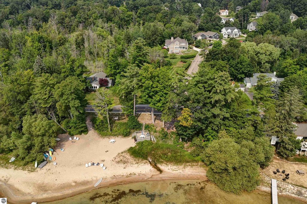 Aerial view of a sandy beach with shared frontage on East Grand Traverse Bay, surrounded by lush trees and residential homes, highlighting the scenic location of the property at 6436 Peregrin Court, Traverse City, MI.