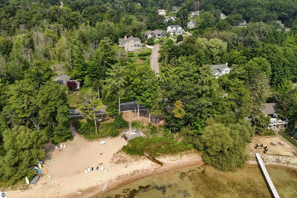 Aerial view of the beach at East Grand Traverse Bay, featuring sandy shoreline, trees, and nearby homes, highlighting the scenic location of 6436 Peregrin Court in Traverse City, MI.