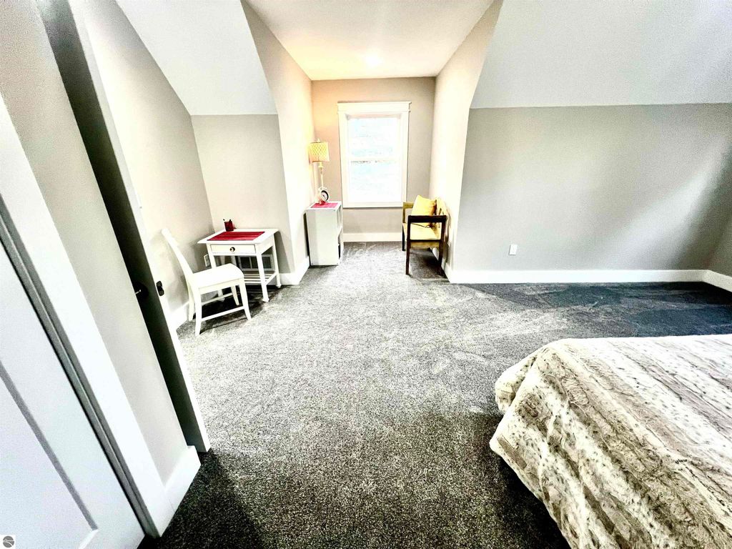 Spacious bedroom in modern home at 2757 Fashion Avenue, featuring cozy seating area, desk, and natural light from window, ideal for studying or relaxation.