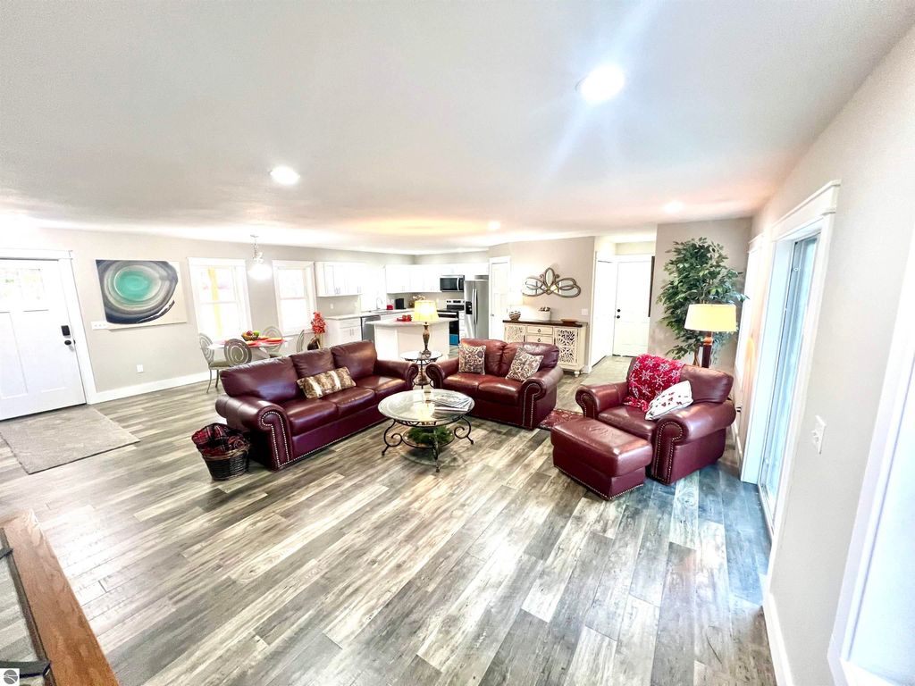 Spacious living room featuring leather sofas, decorative pillows, and a coffee table, showcasing modern design and natural light, ideal for family comfort in the Interlochen home at 2757 Fashion Avenue.