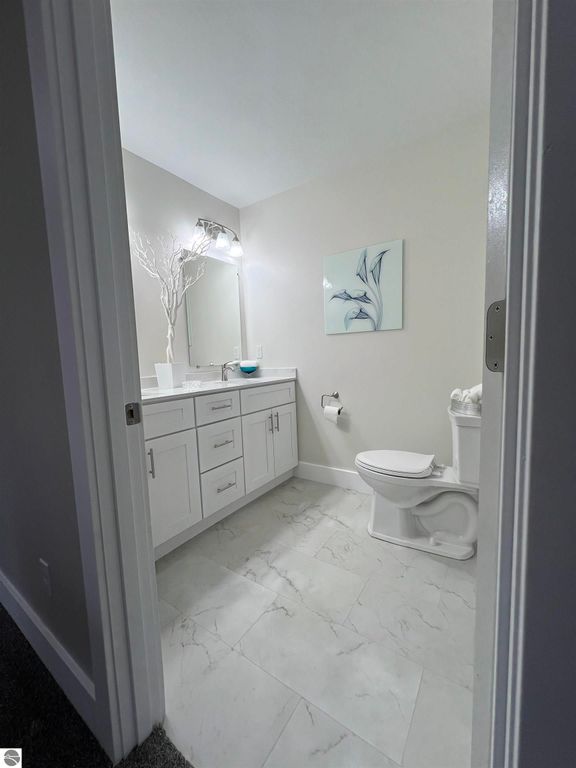 Modern bathroom featuring a white vanity with storage, large mirror, stylish lighting, and decorative wall art, showcasing clean lines and a spacious layout in a home at 2757 Fashion Avenue, Interlochen, MI.