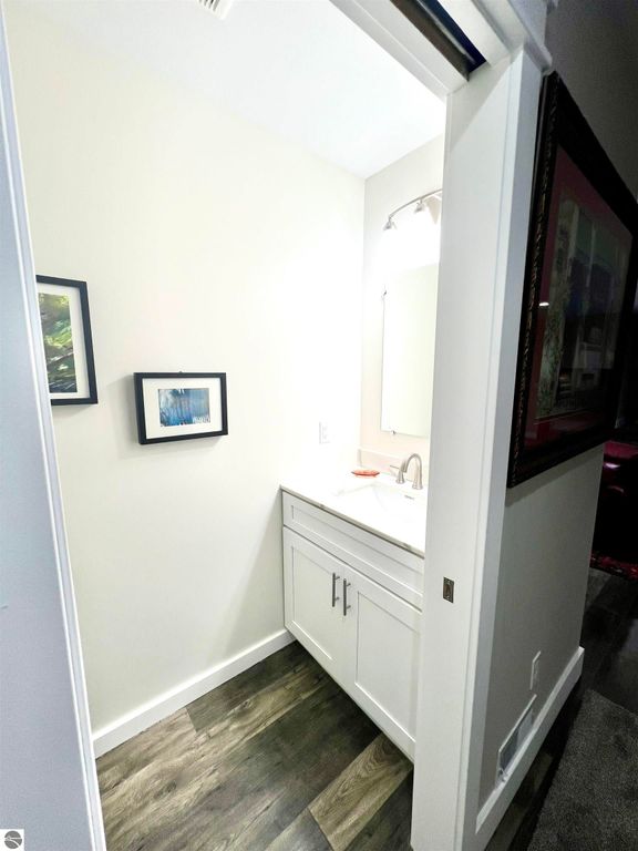 Bathroom interior featuring modern vanity, mirror, framed artwork, and wood flooring, showcasing the home&rsquo;s contemporary design at 2757 Fashion Avenue, Interlochen, MI.