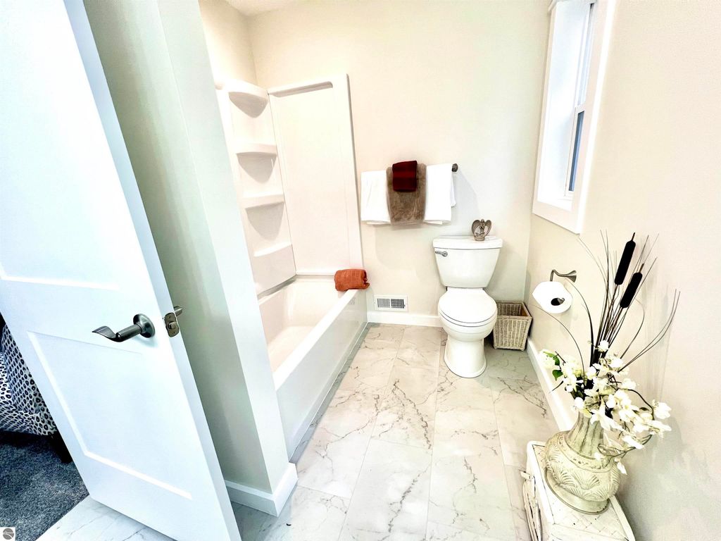 Modern bathroom featuring a bathtub, toilet, and decorative elements, showcasing spacious design and contemporary finishes at 2757 Fashion Avenue, Interlochen, MI.