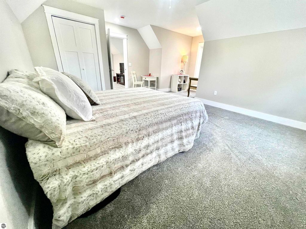 Spacious bedroom with plush bedding and decorative pillows, featuring a cozy ambiance and modern furnishings, part of the real estate listing for 2757 Fashion Avenue, Interlochen, MI.