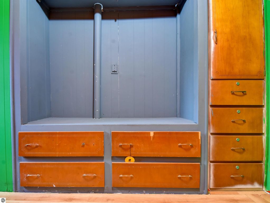 Interior view of a closet featuring multiple wooden drawers and a storage space, showcasing the potential for organization in the 2 bedroom, 1 bathroom home for sale at 974 Parkway Drive, Tawas City, MI.