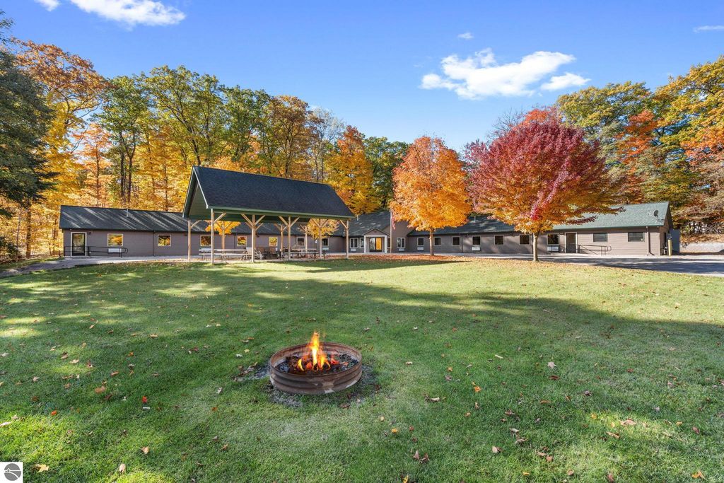 Resort property featuring a 14-unit motel and a 3-bed, 2-bath home in Rapid City, MI, surrounded by vibrant autumn foliage and a fire pit in the foreground.