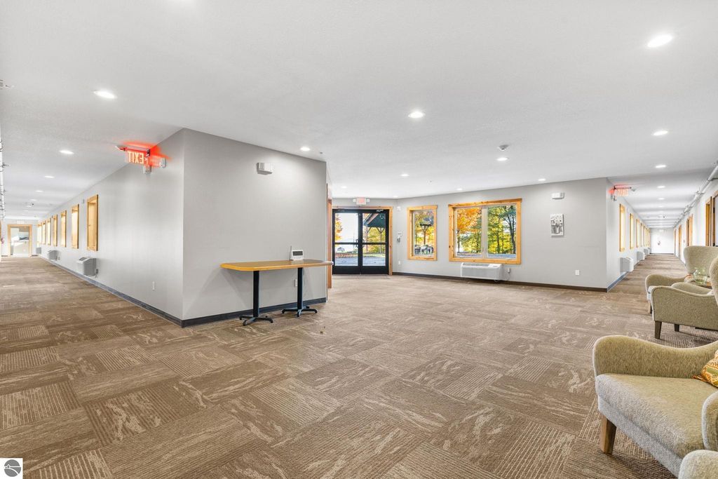 Interior hallway of a motel featuring a reception area with a table, large windows providing natural light, and seating, showcasing the updated and inviting atmosphere of the property for sale at 12800 & 12862 Cherry Avenue, Rapid City, MI.
