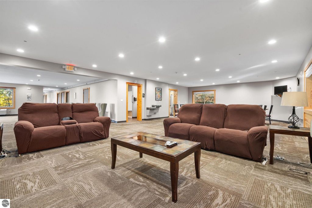 Cozy lounge area with brown sofas, wooden coffee table, and modern lighting, showcasing the inviting interior of a resort property near Torch Lake, ideal for guest relaxation.