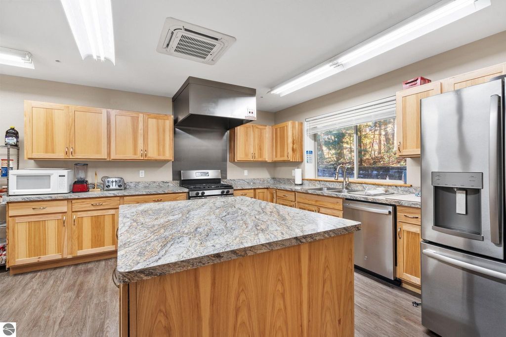 Modern kitchen interior with wooden cabinets, stainless steel appliances, granite countertops, and a window overlooking natural scenery, suitable for a resort property in Rapid City, MI.