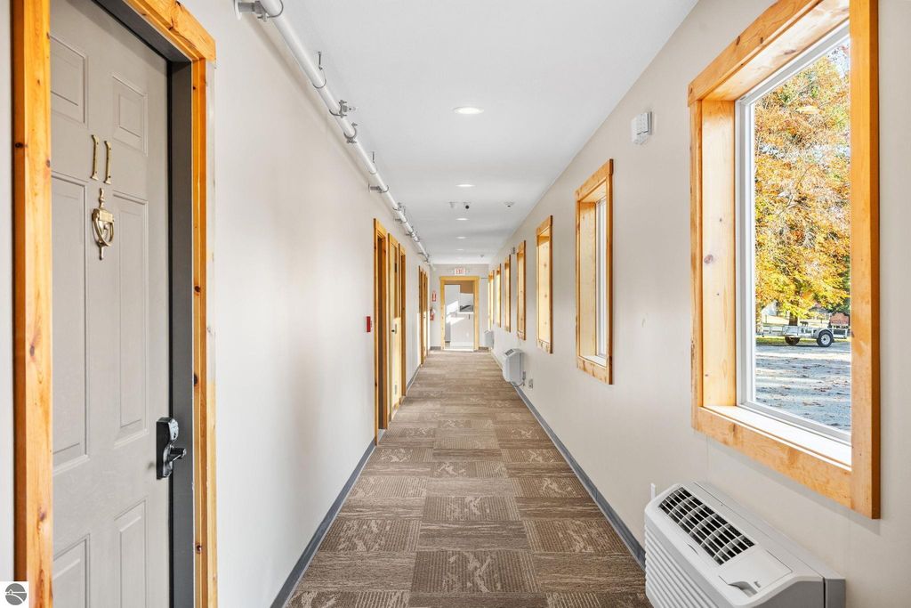 Hallway of updated motel featuring guest room doors, large windows with natural light, and modern decor, highlighting the property at 12800 & 12862 Cherry Avenue, Rapid City, MI.