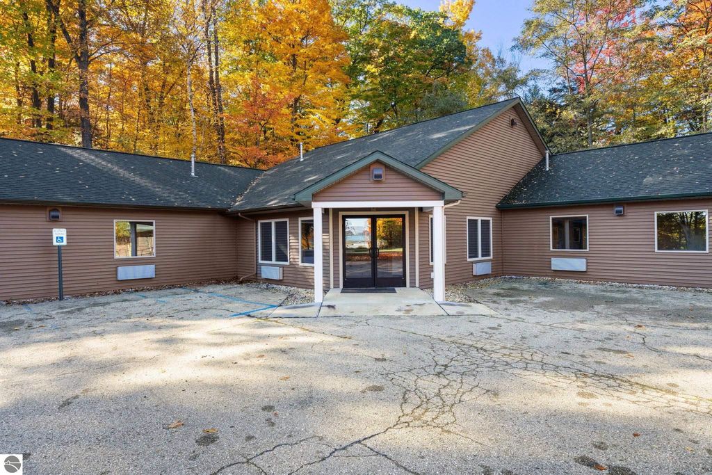 Exterior view of a resort property entrance at 12800 & 12862 Cherry Avenue, surrounded by autumn foliage, featuring a welcoming porch and ample parking space.