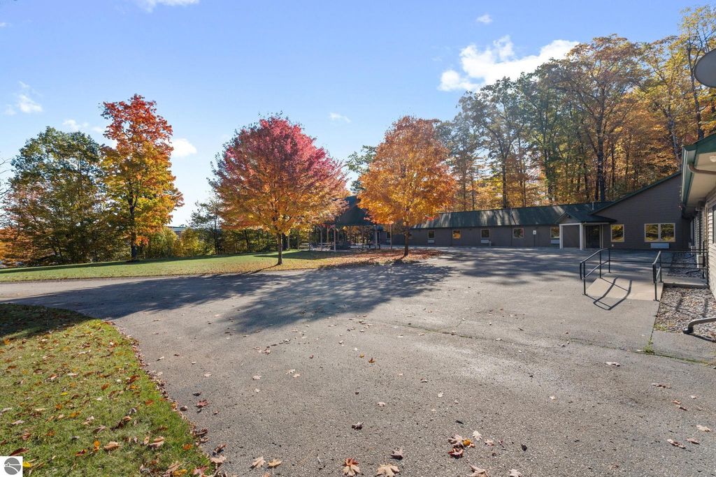 Resort property at 12800 & 12862 Cherry Avenue, Rapid City, MI, featuring fall foliage, updated motel structure, and expansive parking area.