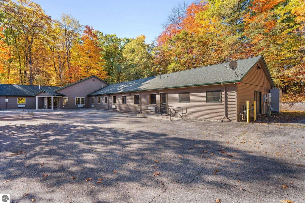 Updated motel building surrounded by colorful autumn foliage, featuring a spacious parking area, ideal for a resort property near Torch Lake in Rapid City, MI.