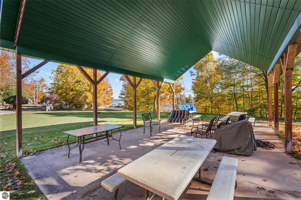 Covered pavilion with seating and tables, surrounded by autumn foliage, near Torch Lake, ideal for outdoor gatherings at the resort property on Cherry Avenue, Rapid City, MI.