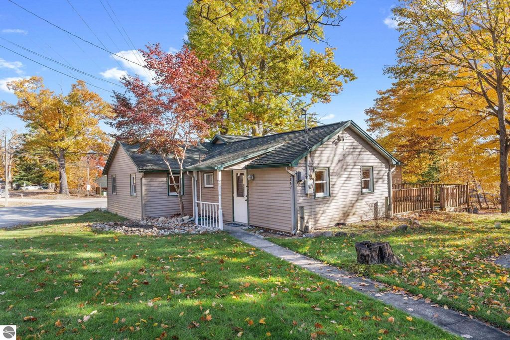 Charming 3-bedroom, 2-bath home on Cherry Avenue, surrounded by vibrant fall foliage, showcasing a welcoming exterior and potential for rental income near Torch Lake.