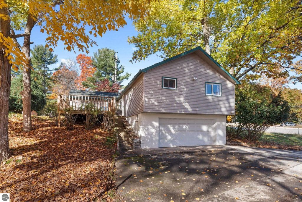 House with a green roof and deck surrounded by colorful autumn foliage, located at 12800 & 12862 Cherry Avenue, Rapid City, MI, ideal for resort property investment near Torch Lake.