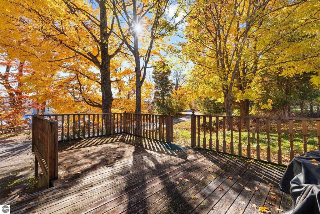 Deck overlooking a vibrant autumn landscape with yellow and orange trees, ideal for enjoying the natural beauty near the resort property at 12800 & 12862 Cherry Avenue, Rapid City, MI.