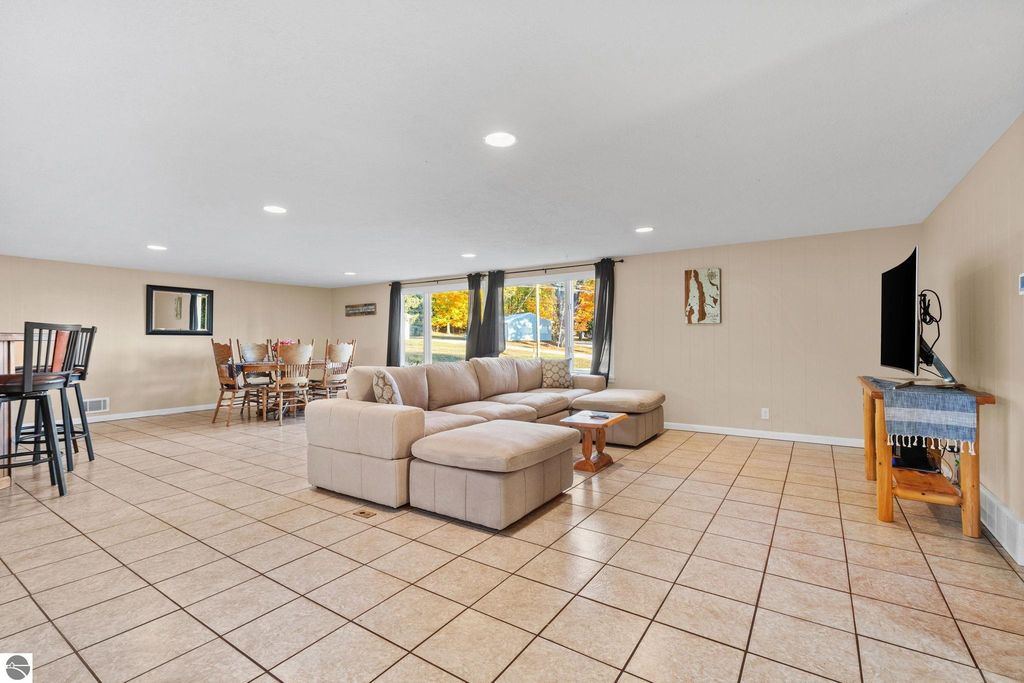 Spacious living area featuring a sectional sofa, dining table, and large windows, ideal for guests at the resort property near Torch Lake.