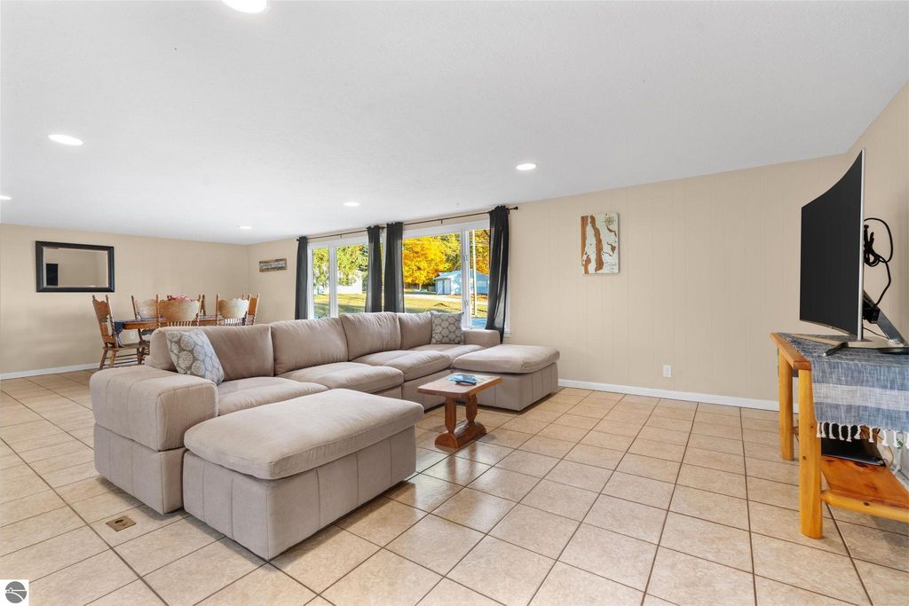 Spacious living area featuring a sectional sofa, dining table, and large windows with views of the outdoors, highlighting the inviting interior of the property at 12800 & 12862 Cherry Avenue, Rapid City, MI.