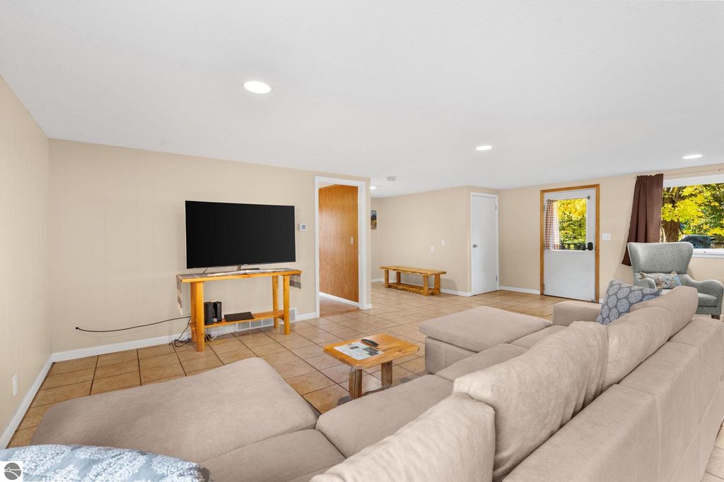 Spacious living area in a resort property featuring a large flat-screen TV, comfortable sectional sofa, and natural light from windows, showcasing an inviting atmosphere for guests at 12800 & 12862 Cherry Avenue, Rapid City, MI.