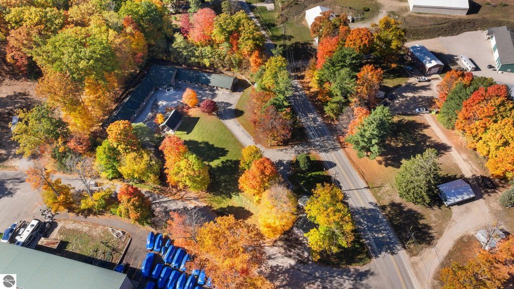 Aerial view of a resort property on Cherry Avenue, surrounded by vibrant autumn foliage, featuring a motel complex and expansive green space, highlighting the appeal of the Torch Lake area in Northern Michigan.