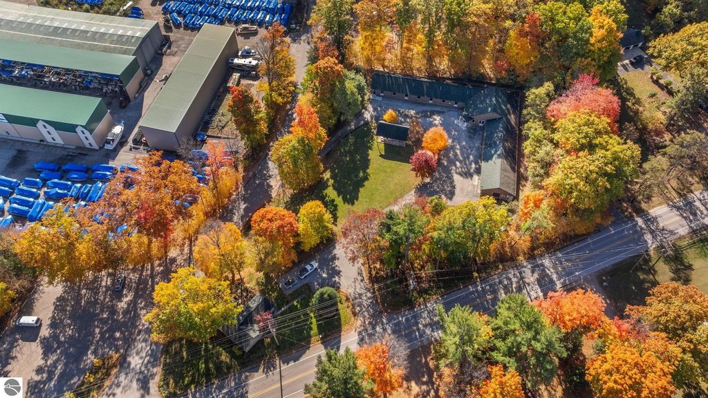 Aerial view of a resort property at 12800 & 12862 Cherry Avenue, Rapid City, MI, featuring a 14-unit motel, surrounded by vibrant autumn foliage and nearby commercial buildings.