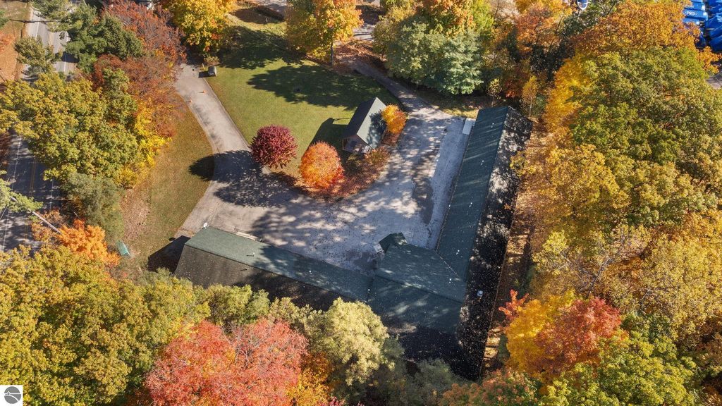 Aerial view of a resort property in Rapid City, MI, featuring a 14-unit motel and a spacious lawn surrounded by vibrant autumn foliage, ideal for vacation rentals near Torch Lake.
